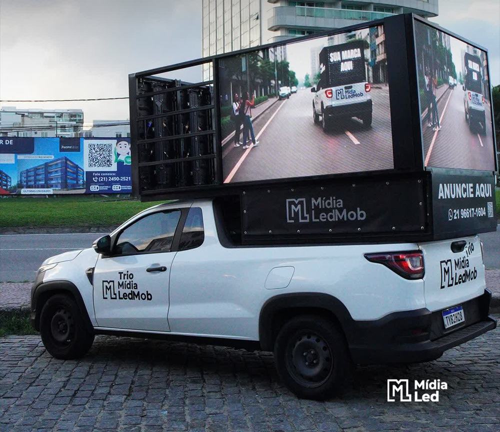 Trio Mídia LedMob com o painel de LED aceso, veiculando em avenida de Nova Iguaçu